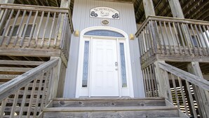 A wooden staircase leading to a white door with a sign above it reading "Schemering Seas" and the number "1066". - Semi-Oceanfront, Private Pool, Hot Tub, Close to beach! WL1066, Schemering Seas (Corolla)
