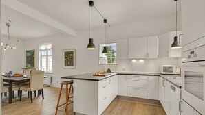 A modern kitchen with white cabinets, a wooden island, and pendant lighting. - Stunning home in Kværndrup with WiFi (Kværndrup)