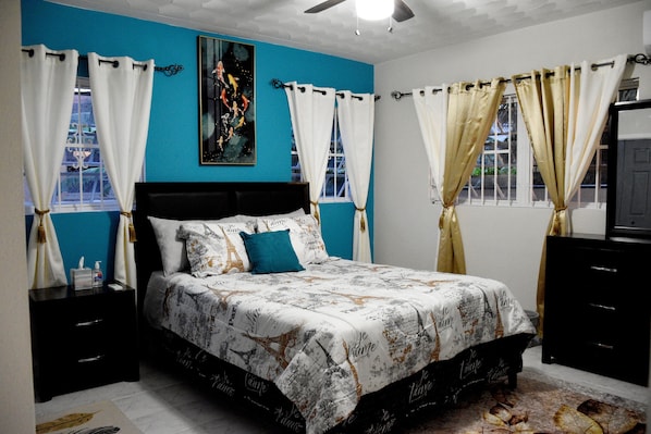 A bedroom with a bed, nightstands, a ceiling fan, and curtains.