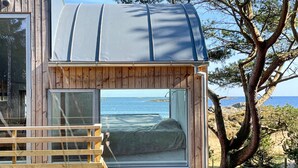 Une petite cabane en bois dotée d’une grande fenêtre donnant sur la mer.