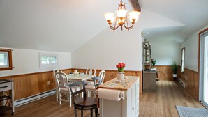 A dining area with a wooden table, chairs, a chandelier, and a kitchen area with a ladder and potted plant. - Dog friendly hideaway in Bucks County near River (Bensalem)