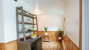 A narrow hallway with wooden flooring and walls, a wooden ladder shelf with potted plants, a small table with a bowl of fruit, and a potted plant on a wooden stool. - Dog friendly hideaway in Bucks County near River (Bensalem)