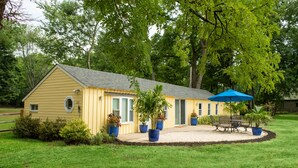 A yellow single-story house with a covered patio, surrounded by a well-maintained lawn and trees. - Dog friendly hideaway in Bucks County near River (Bensalem)