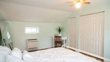 A bedroom with a bed, a desk, a chair, a ceiling fan, and a closet.