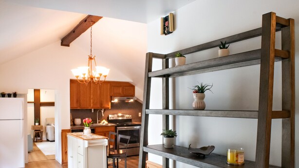 A modern kitchen with wooden cabinets, a built-in shelf unit, a chandelier, and a dining area with a wooden table and chairs. - Dog friendly hideaway in Bucks County near River (Bensalem)