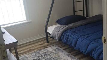 Une chambre avec un lit superposé, un petit bureau et une fenêtre.