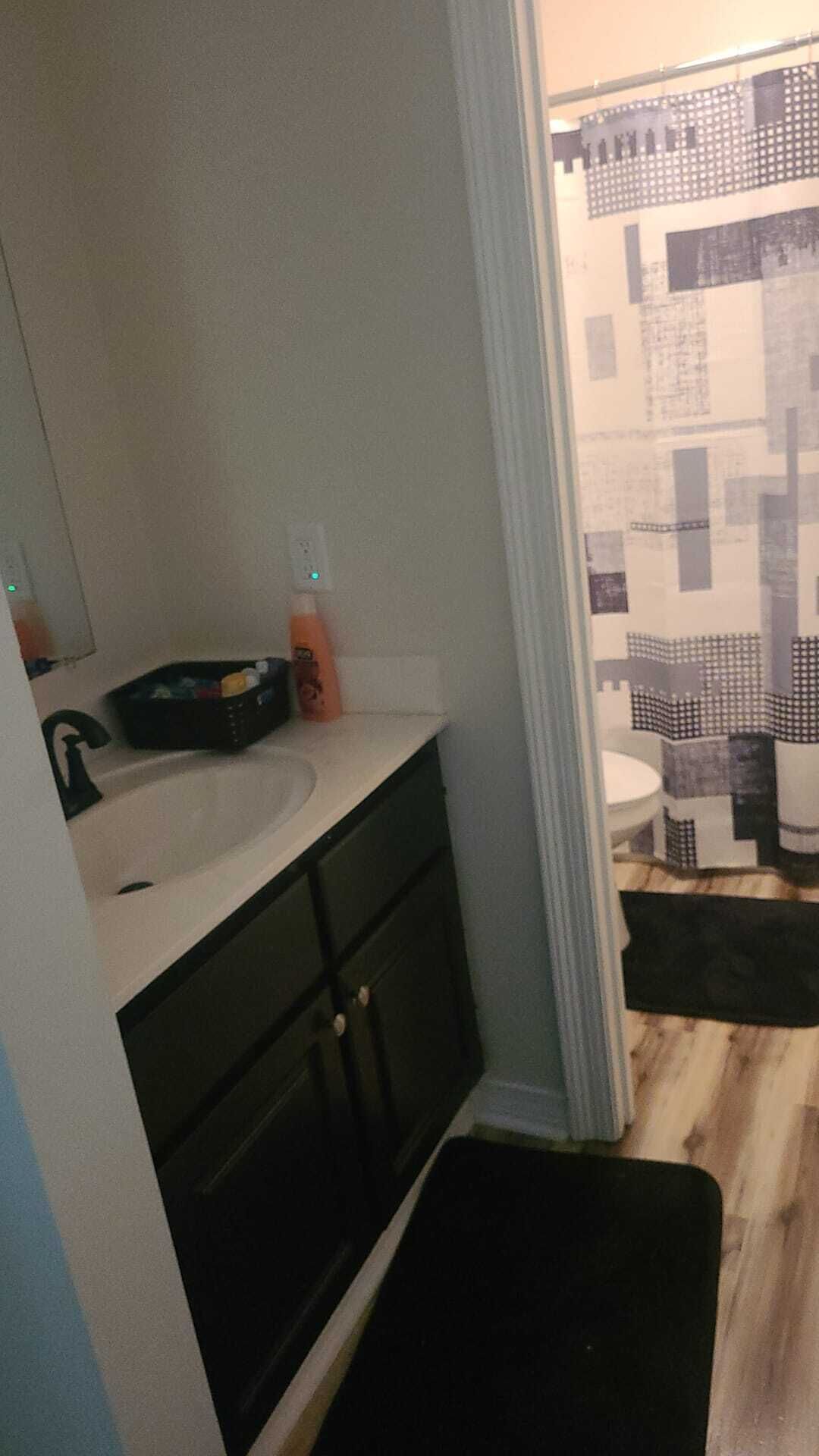 A bathroom with a white sink, dark cabinets, and a shower curtain with a geometric pattern.
