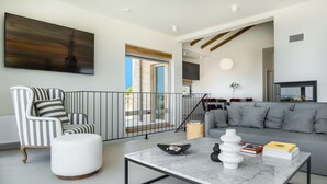 Una sala de estar moderna con un sillón a rayas, un sofá gris y una mesa de centro de mármol.