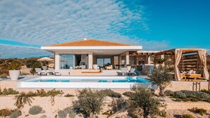 Una casa moderna con piscina, mobiliario exterior y una pérgola.
