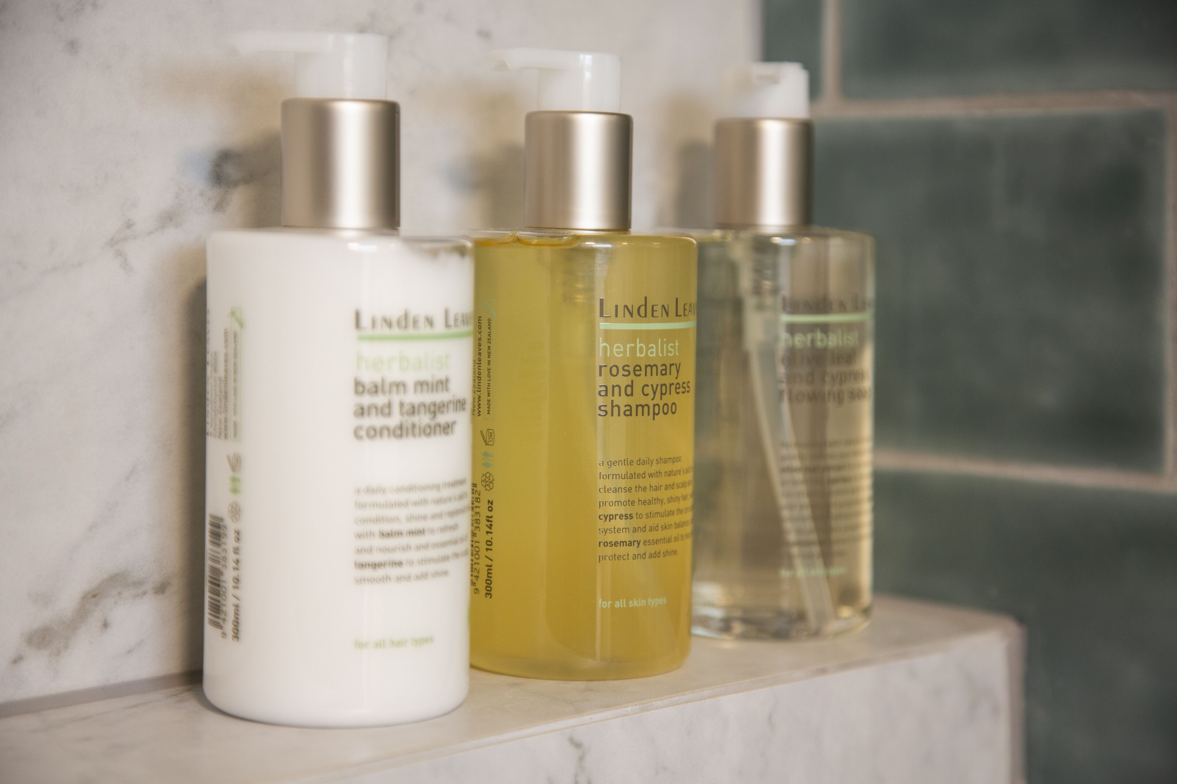 Tres botellas de productos herbales LINDEN LEE sobre una superficie de mármol.