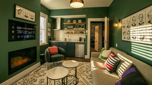 A living room with a fireplace, a sofa, a coffee table, and a television mounted on the wall. - The Vicarage Geraldine (Geraldine)