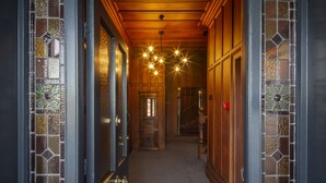 A hallway with wooden paneling, a chandelier, and a stained glass door. - The Vicarage Geraldine (Geraldine)