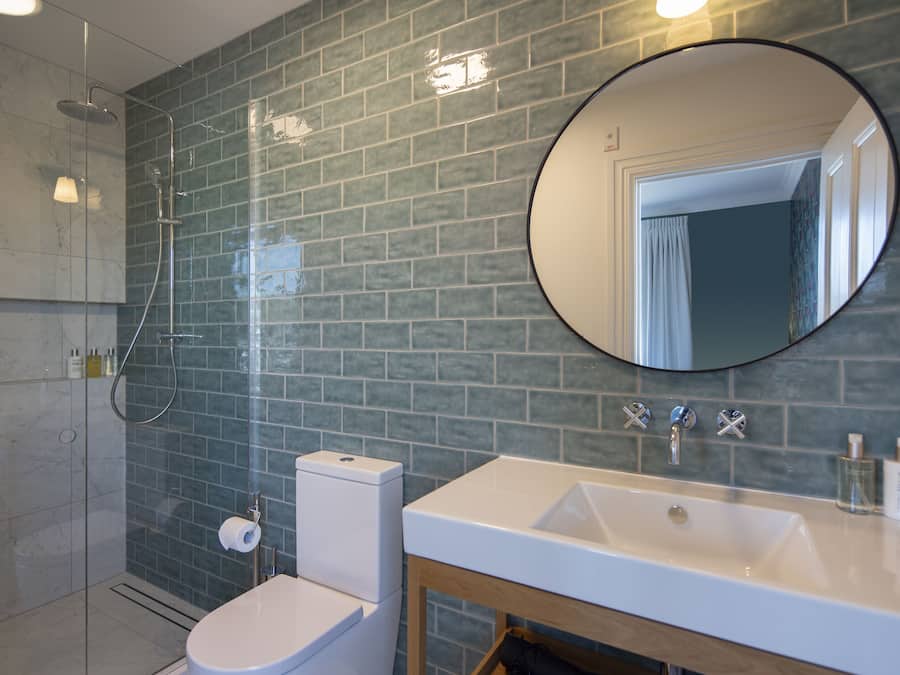 A modern bathroom with a glass-enclosed shower, a white toilet, and a sink with a mirror above it.