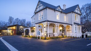 A large, two-story building with a porch and a sign that reads "Woodstove Bakery." - The Vicarage Geraldine (Geraldine)