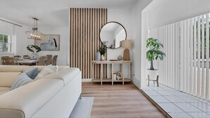 A modern living room with a sofa, dining table, and a large window with blinds. - Newly remodeled beach house by Lido Beach and private pool (Sarasota)