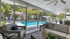 A modern outdoor living area with a pool, lounge chairs, and a ceiling fan. - Newly remodeled beach house by Lido Beach and private pool (Sarasota)