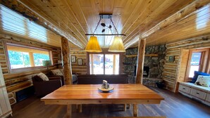 Ein rustikales Blockhaus mit einem Holzesstisch, Bänken und einem Kamin aus Stein.