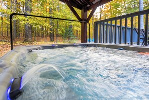 A hot tub with a wooden deck and railing, surrounded by trees in autumn colors. - Total Seclusion! Hot tub,  Traverse City downtown 10 min, Booking for summer!  (Traverse City)
