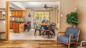 A spacious dining area with a wooden table and chairs, a ceiling fan, and a view through a large window. - Total Seclusion! Hot tub,  Traverse City downtown 10 min, Booking for summer!  (Traverse City)