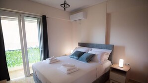 A bedroom with a bed, a nightstand, an air conditioning unit, and a view of greenery outside. - Athens & Acropolis View 7th Floor Apartment (Athens)