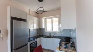A modern kitchen with white cabinets, a stainless steel refrigerator, and a black countertop. - Athens & Acropolis View 7th Floor Apartment (Athens)