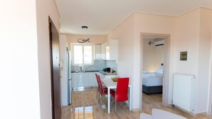 A modern kitchen with white cabinets, a dining table with red chairs, and a visible ceiling light fixture. - Athens & Acropolis View 7th Floor Apartment (Athens)