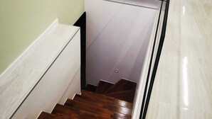 A staircase with wooden steps and a glass railing, leading to a room with a white wall and a glass table with chairs. - Villa Marijo with sea view and pool, Croatia (Razanj)
