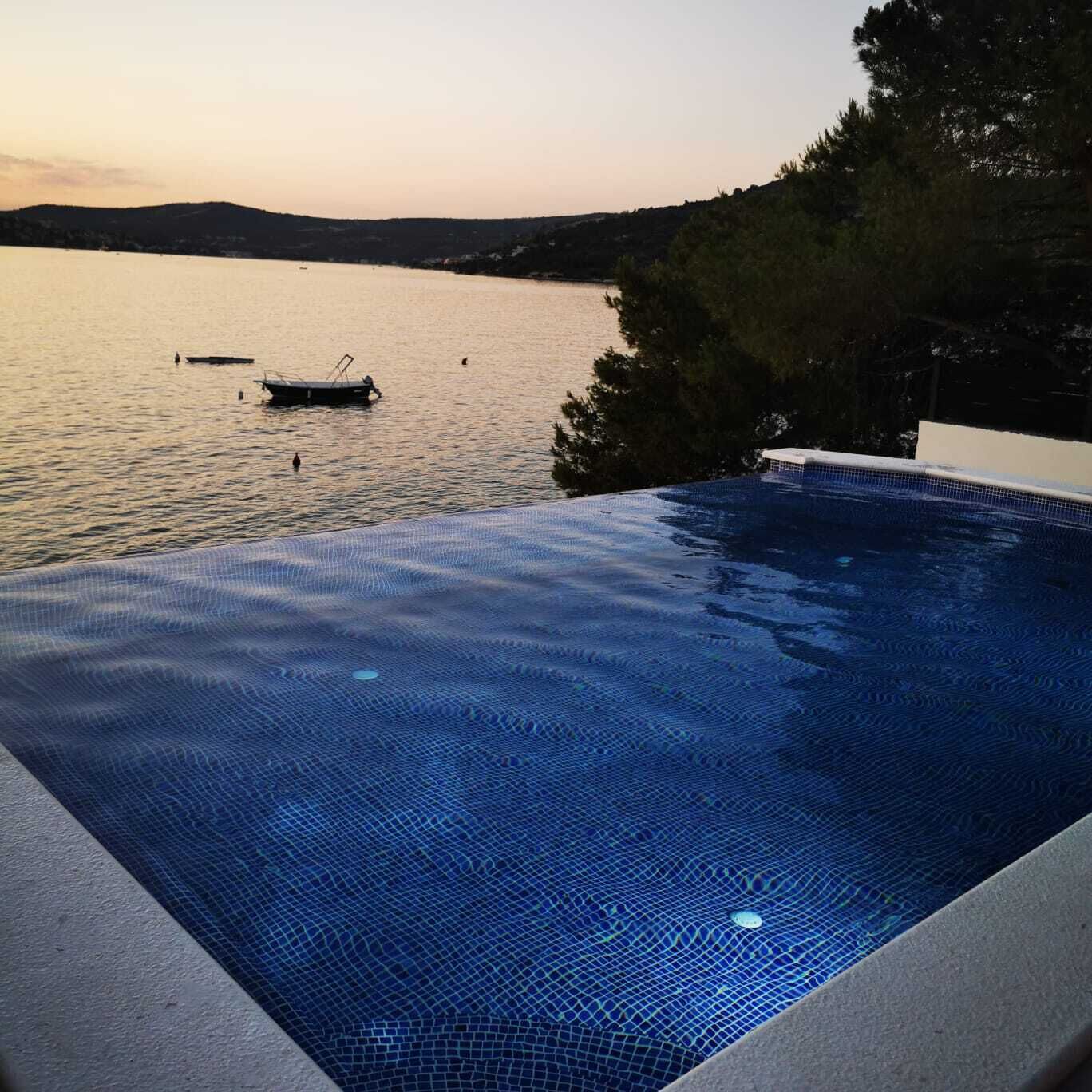 En swimmingpool med utsikt över en sjö och kullar i bakgrunden.