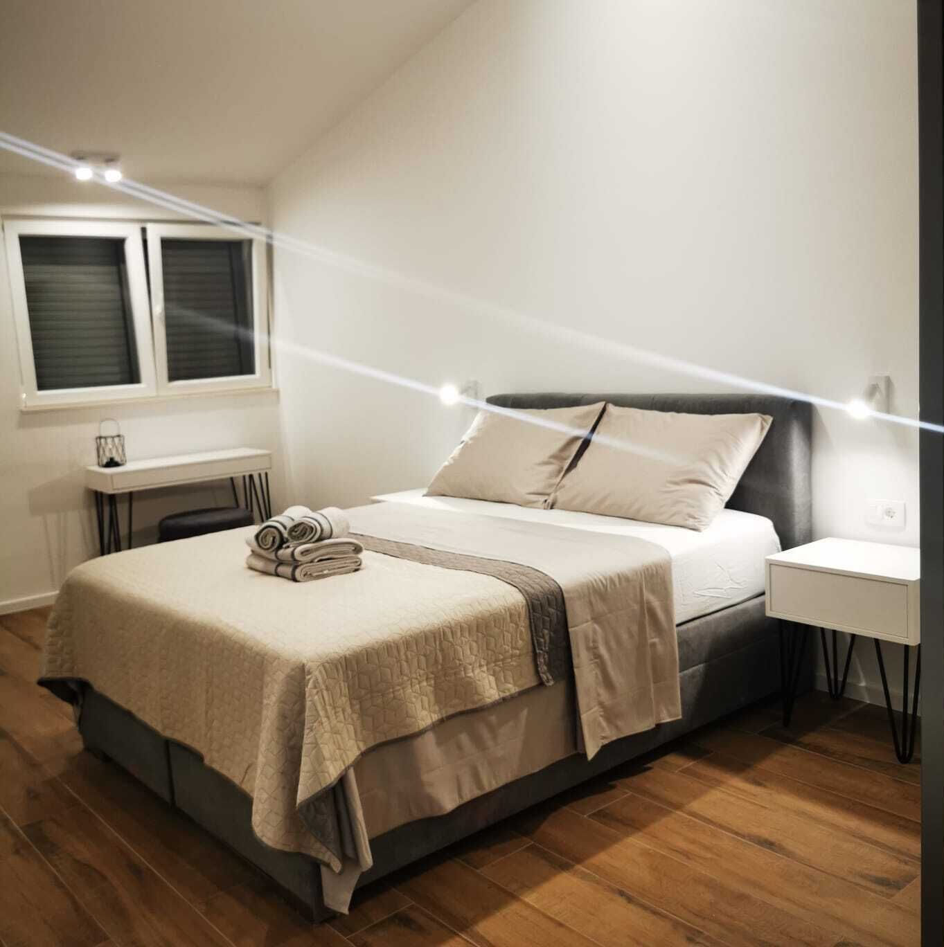 Une chambre à coucher moderne avec un lit, des tables de chevet et une fenêtre.