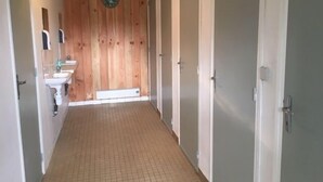 A narrow hallway with a wooden wall, a clock, a sink, and doors leading to rooms. - Unique & serene 1-Bed Cabin close to Domfront (Domfront)