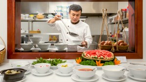 Un chef sirve comida detrás de una barra con varios platos y una sandía decorativa como centro de mesa.