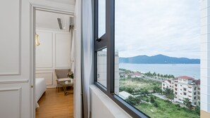 Una habitación de hotel con un ventanal grande, una cama, un sofá y una pequeña mesa con un florero.