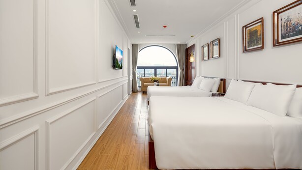 Un cuarto de hotel con una cama grande, un sofá y vista de la ciudad a través de un ventanal.