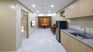 A modern kitchen with a built-in sink, wooden cabinets, and a dining area with a table and chairs. - Cebu Family Suites powered by Cocotel (Cebu City)