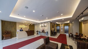 A hotel lobby with a reception desk, seating area, and a red carpet. - Cebu Family Suites powered by Cocotel (Cebu City)
