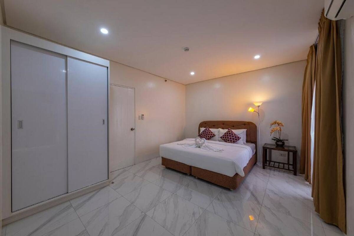 Une chambre à coucher avec un lit, une armoire, une table de chevet et une lampe.