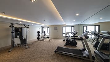 Un gimnasio con cintas de correr, máquinas de pesas y un espejo grande.