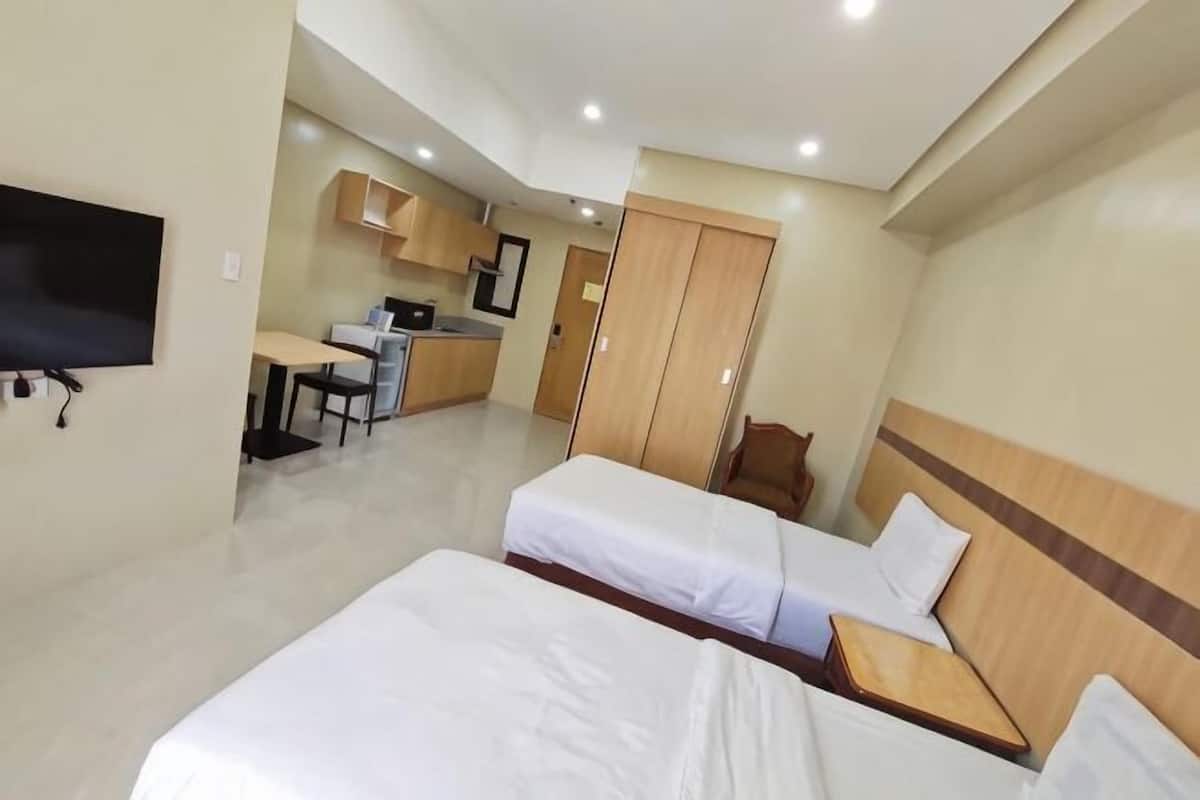 Une chambre d’hôtel avec deux lits, une télévision, un coin cuisine et un bureau.