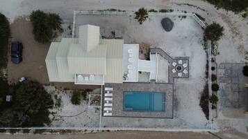 An aerial view of a property with a swimming pool, outdoor seating area, and a covered patio.