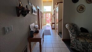 Un couloir avec un plafond en bois, un banc, un canapé et une porte qui donne sur une pièce lumineuse.