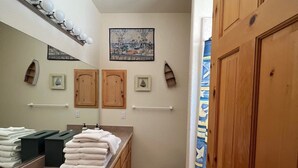 Une salle de bain équipée d’un lavabo, d’un miroir, d’un porte-serviettes et d’armoires en bois.