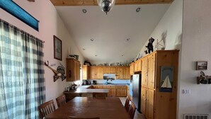 Une cuisine spacieuse dotée de meubles en bois, d’un îlot central et d’un coin repas avec une grande table et des chaises en bois.