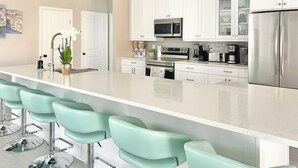 Una cocina moderna con armarios blancos, electrodomésticos de acero inoxidable y una isla grande con taburetes de bar.