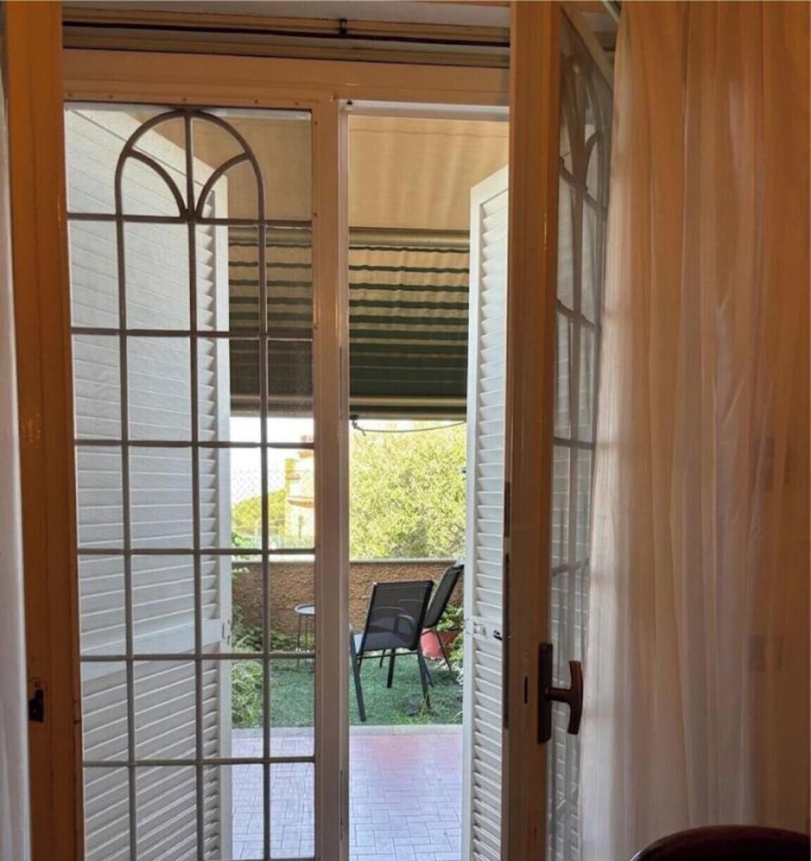 Eine Tür mit Rastermuster, die zu einem Außenbereich mit Terrasse und Stühlen führt.