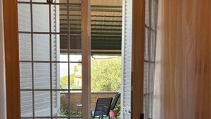Une porte à motifs géométriques donnant sur un espace extérieur comprenant une terrasse et des chaises.