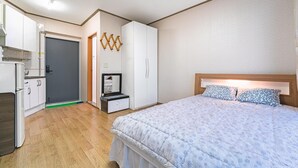 A bedroom with a bed, a dresser, a mirror, and a wardrobe.
