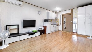 A modern kitchen with a flat-screen TV, microwave, and refrigerator.