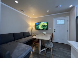 Cozy living space with a sofa, dining table, and flat-screen TV.