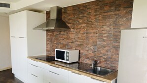 A kitchen with white cabinets, a stainless steel sink, a microwave, and a brick backsplash. - Sea view apartment, 5 min drive from Kata Beach (Karon)