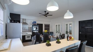 Una cocina moderna con una isla central, comedor y una puerta negra.